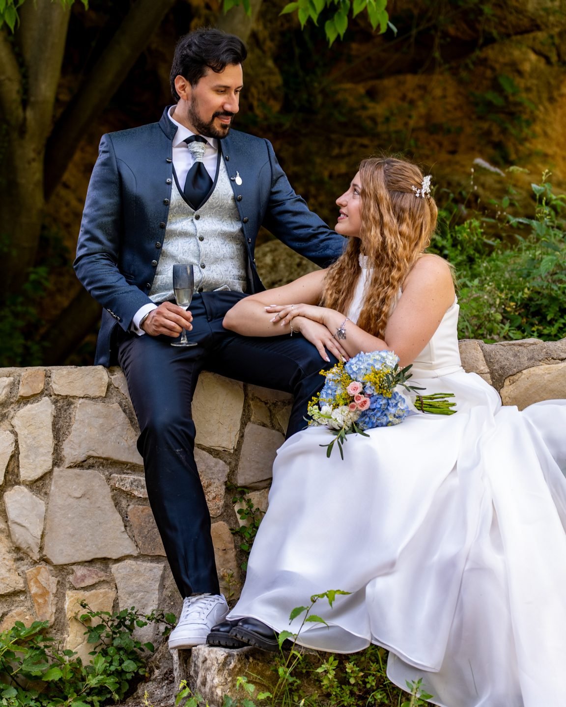 Novios sentados sobre un muro de piedra