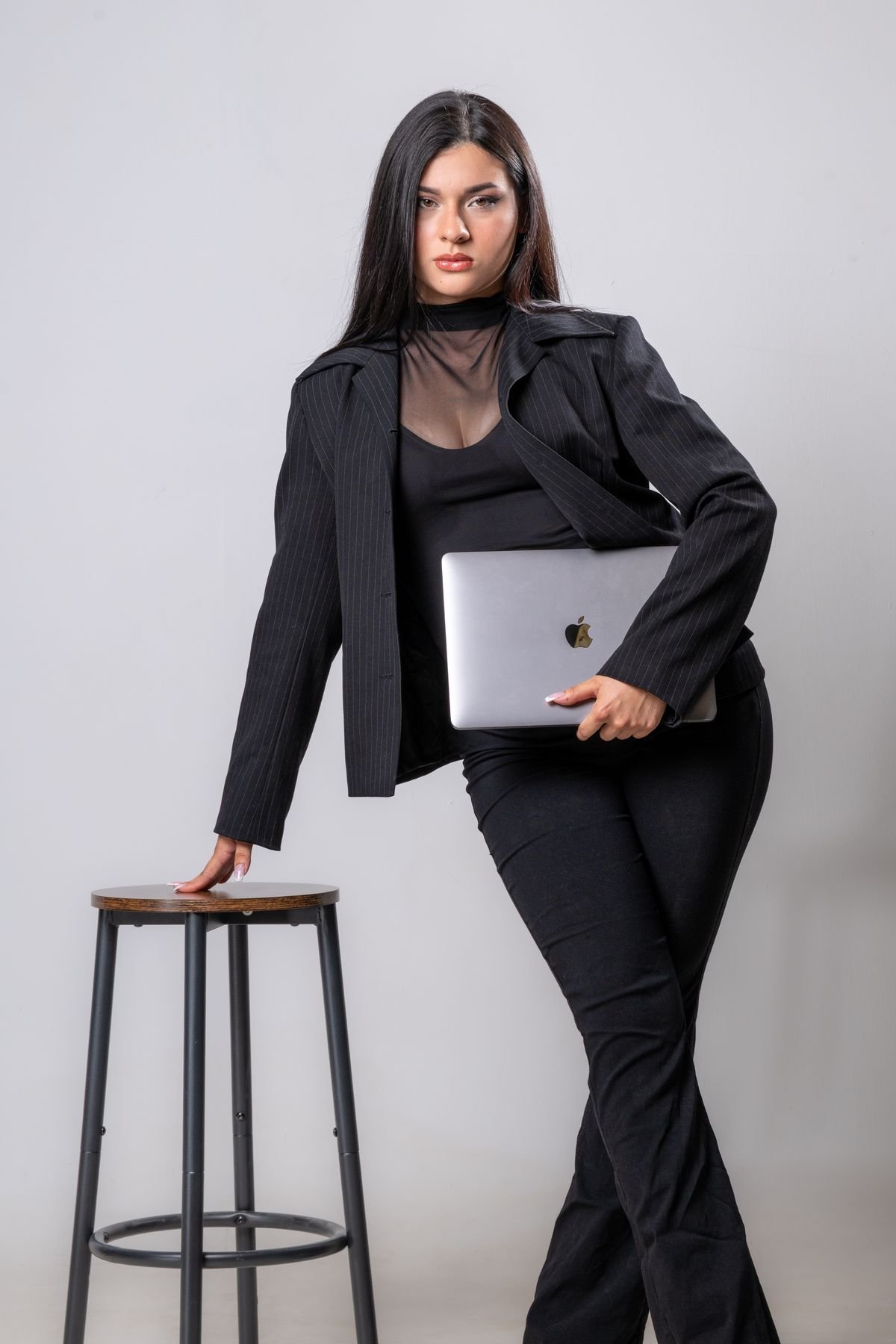 Retrato con traje y portátil junto a un taburete