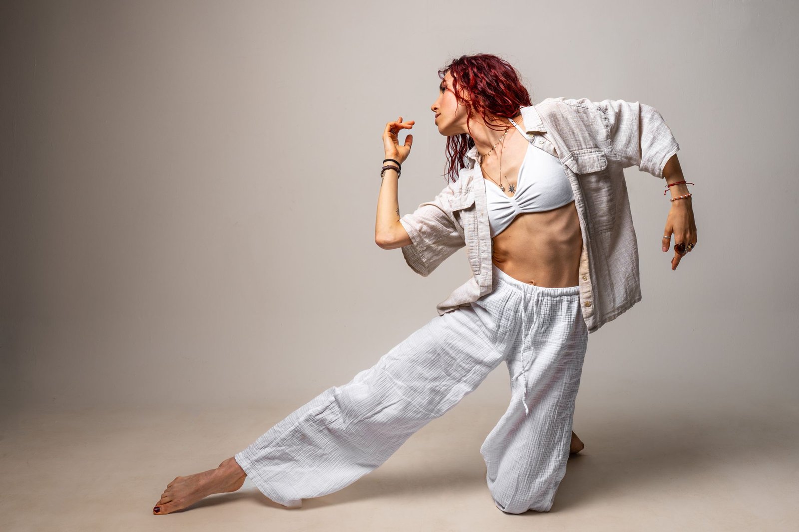 Pose de danza arrodillada con ropa blanca