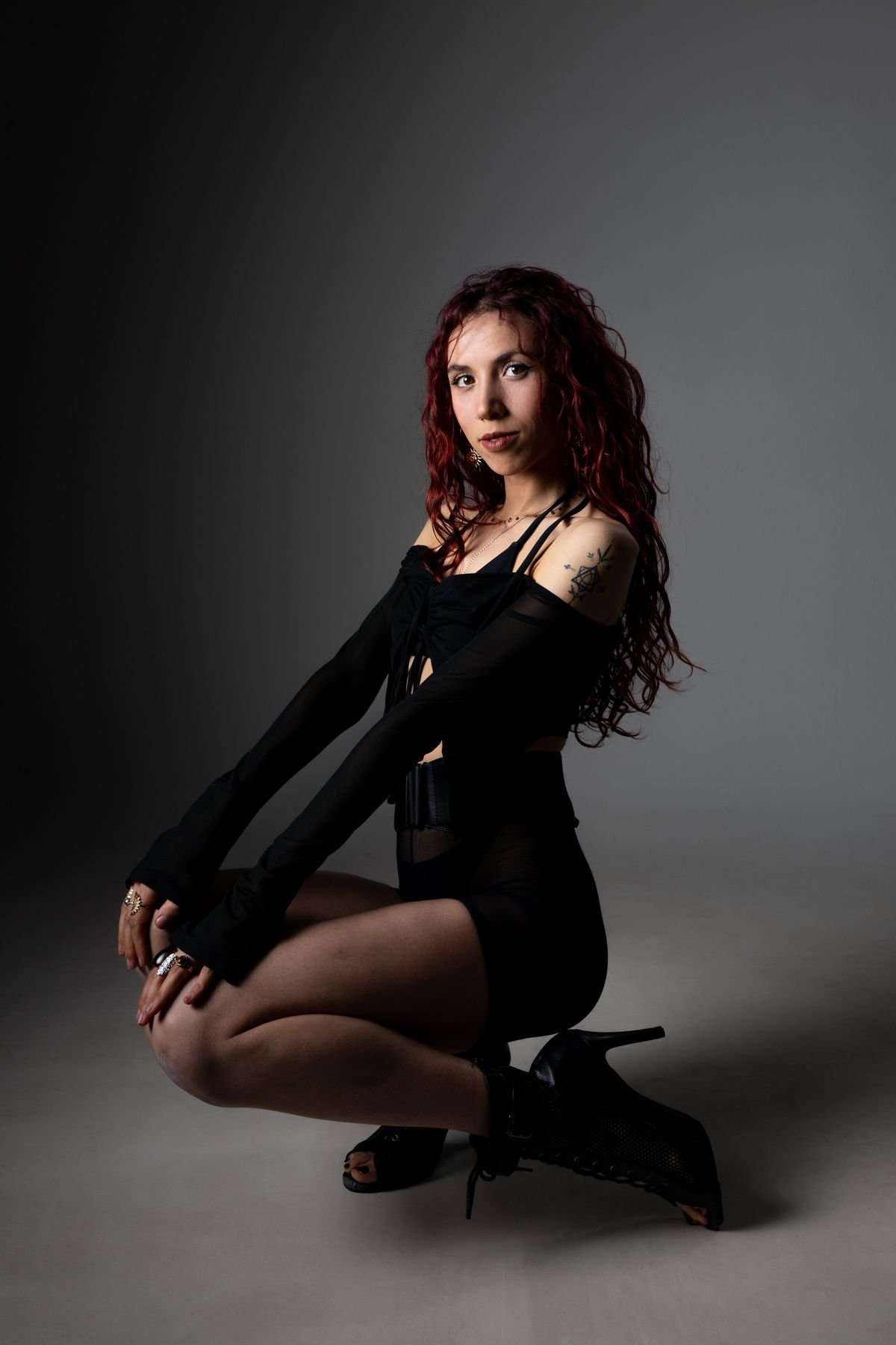 Retrato agachada con tacones sobre fondo oscuro