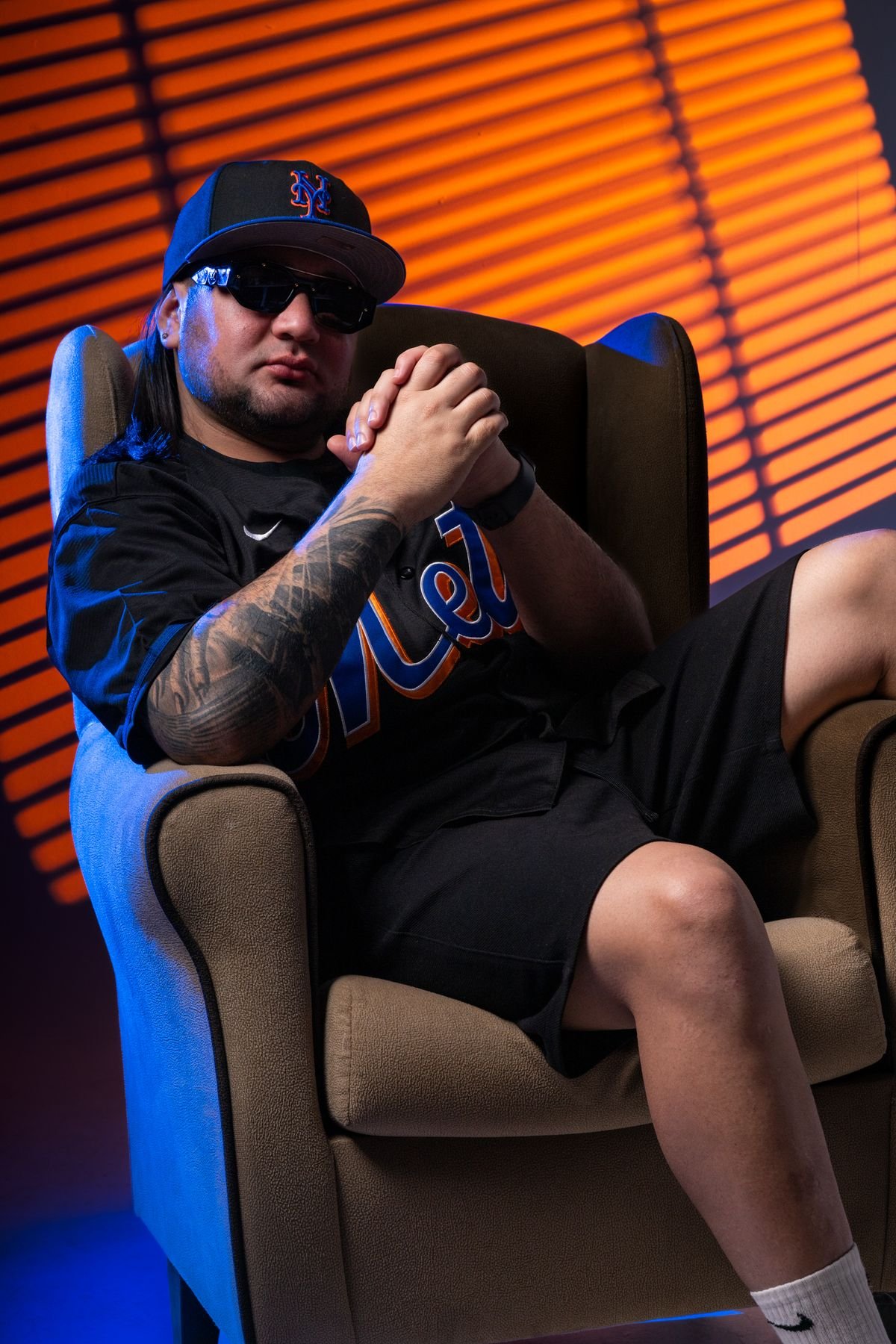 Sentado en un sillón con camiseta de béisbol y persianas de luz