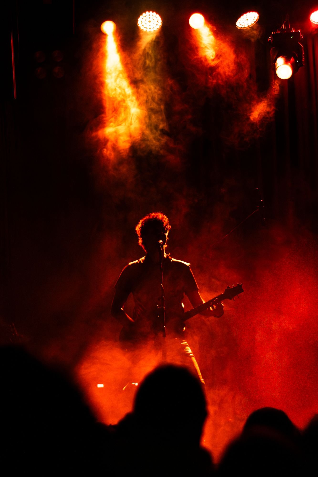 Guitarrista a contraluz entre humo rojo