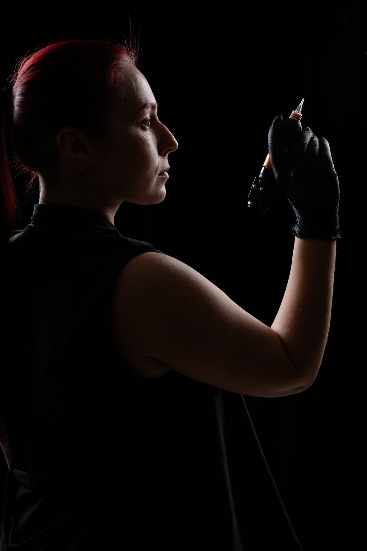 Tatuadora de perfil a contraluz con la máquina