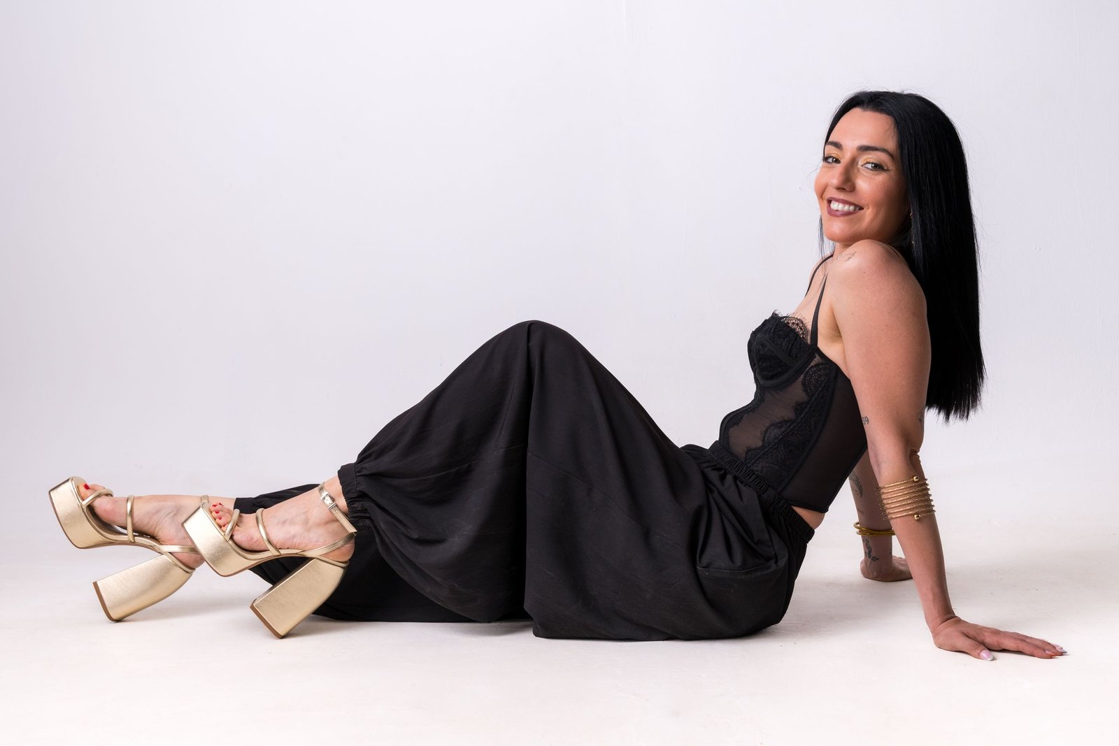 Mujer sentada en el suelo con sandalias doradas