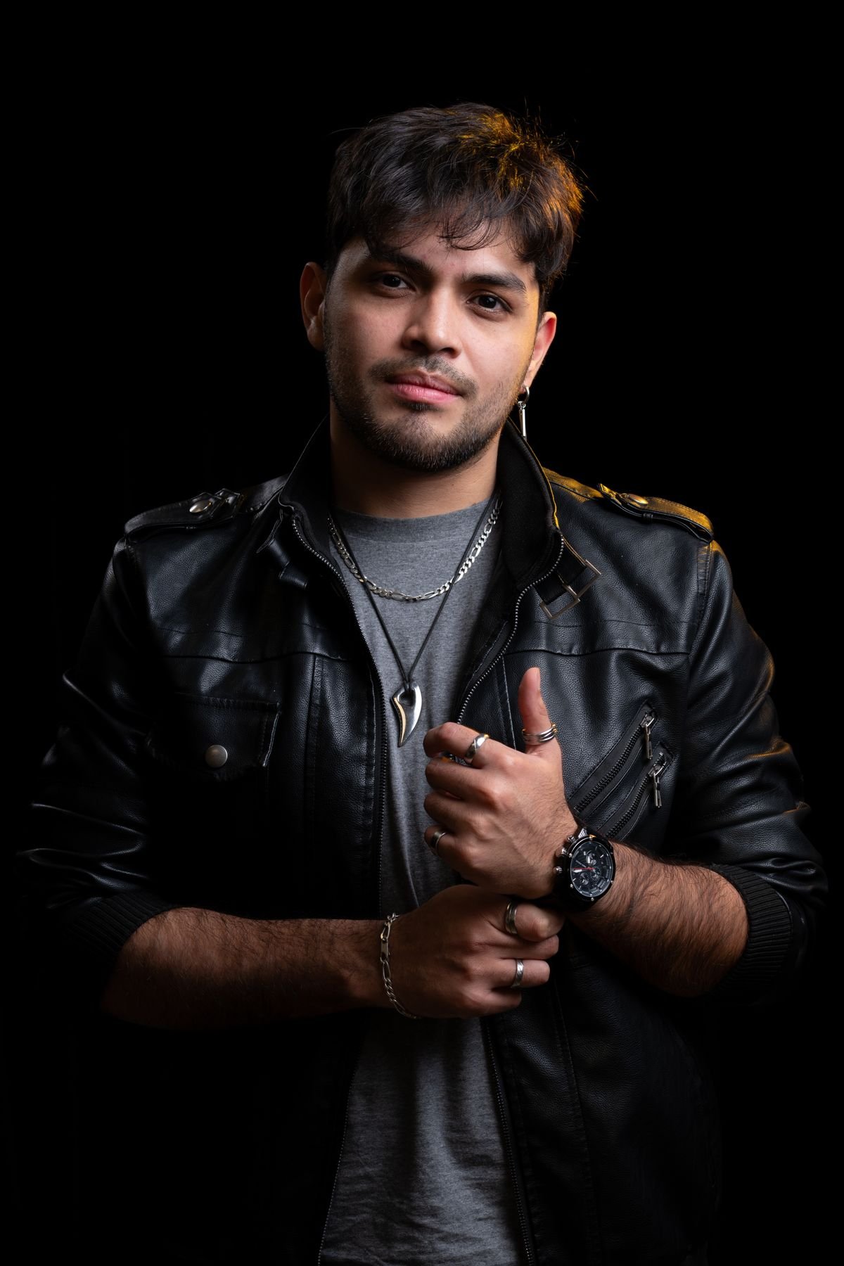 Chico con chaqueta de cuero y anillos sobre fondo negro